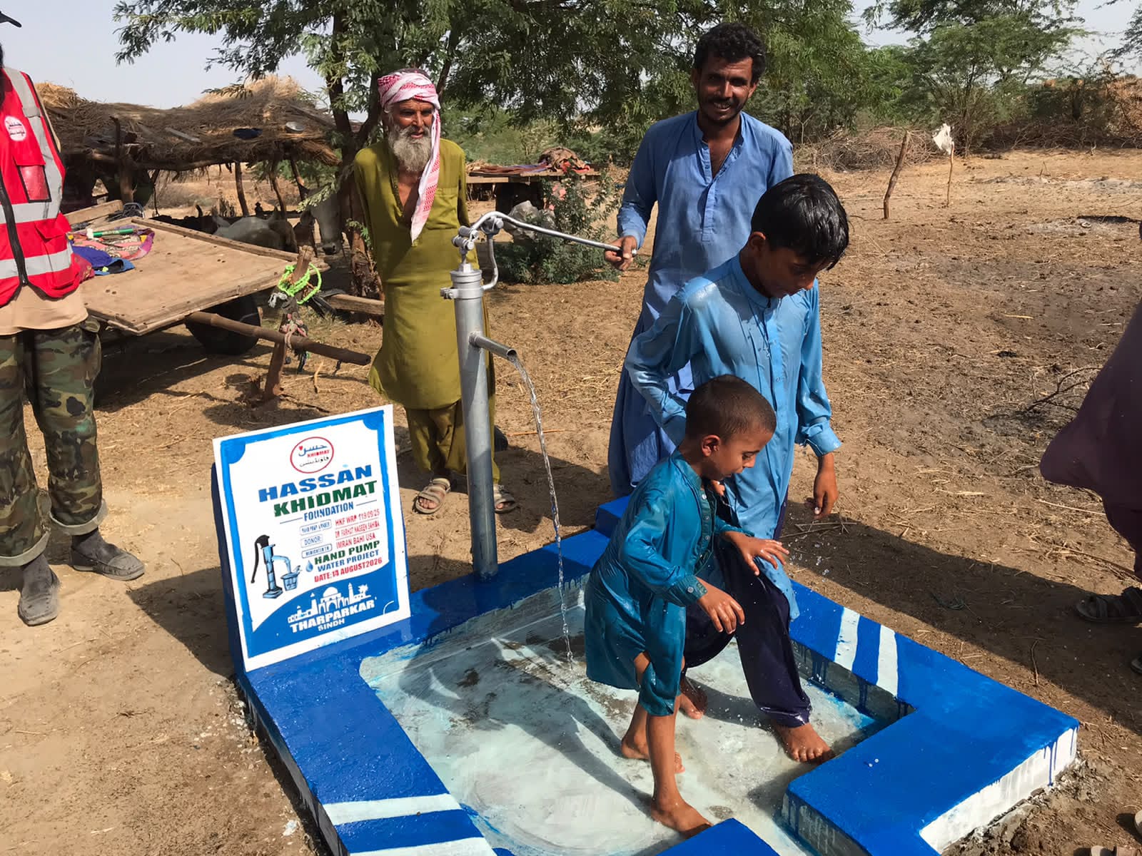 Child drawing water while the field team observes