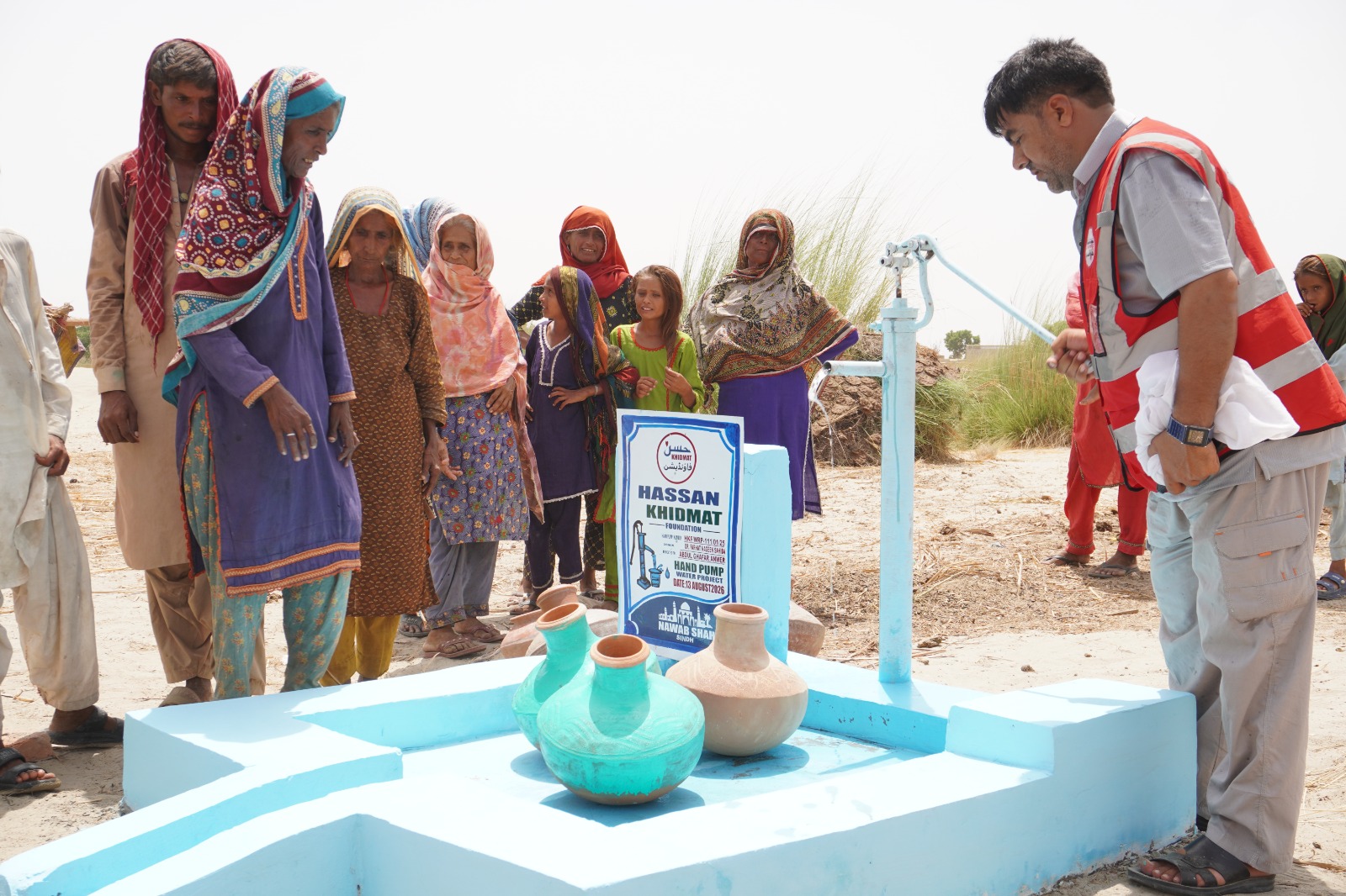 Women and children collecting water from a newly installed hand pump